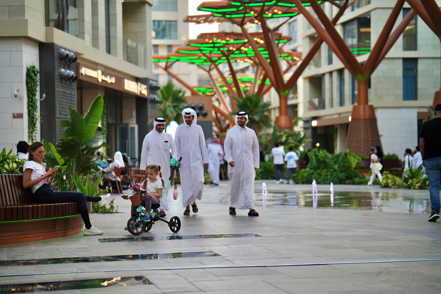 People walking and sitting in a modern urban pedestrian plaza.